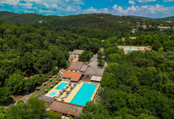Luchtbeeld van Camping La Clémentine in Occitanië, Frankrijk, met zwembaden te midden van bosrijk gebied.