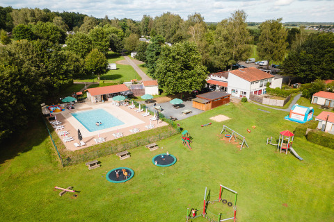 Vista aerea di Camping La Colline in Belgio con piscina, area giochi e tanto verde nel villaggio vacanze.