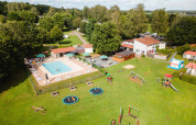 Vista aerea di Camping La Colline in Belgio con piscina, area giochi e tanto verde nel villaggio vacanze.