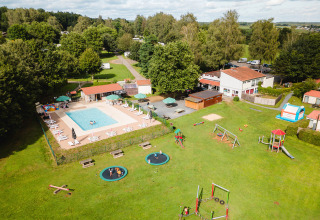 Aerial view of Camping La Colline in Belgium featuring a pool, playground, and plenty of green space.