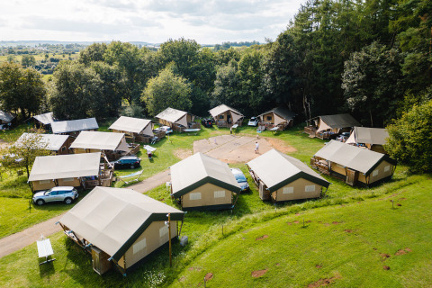 Vista aérea de Camping La Colline con tiendas tipo safari, coches y zonas verdes en Luxemburgo, Bélgica.