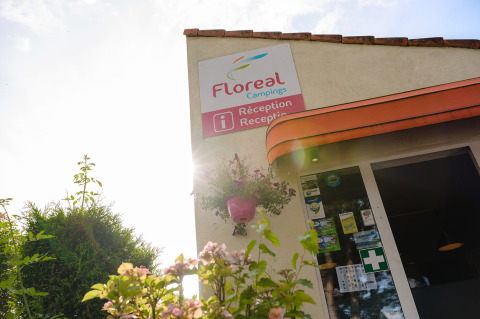 Entrance of Floreal Campings La Colline holiday park, reception sign with flowers and sunlight, Belgium.