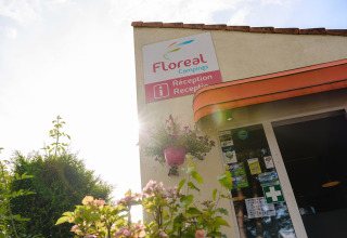 Entrance of Floreal Campings La Colline holiday park, reception sign with flowers and sunlight, Belgium.
