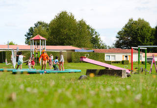 Kinderen spelen op de speelplaats van Camping La Colline, een vakantiepark omringd door groen in België.