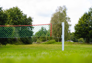 Camping La Colline: Volleybalnet op grasveld omringd door bomen in vakantiepark in België Luxemburg.