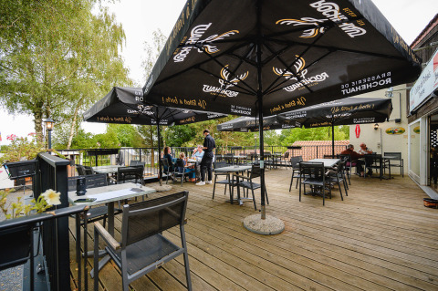 Area pranzo all'aperto con ombrelloni e terrazza in legno presso Camping La Colline, Belgio Lussemburgo.
