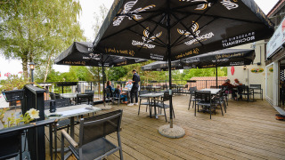 Zona de comedor al aire libre con sombrillas y terraza de madera en Camping La Colline, Belgio Luxemburgo, Bélgica.