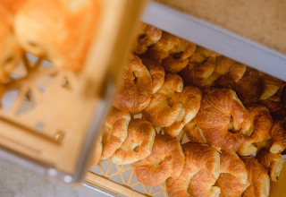 Versgebakken croissants in een plastic bak bij Camping La Colline, vakantiedomein in België Luxemburg, België.