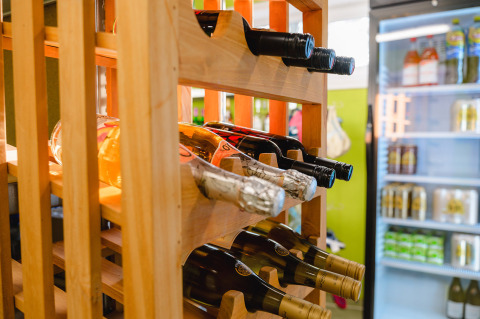 Wine bottles stored in a wooden rack next to a fridge at Camping La Colline holiday park in Belgium Luxembourg.