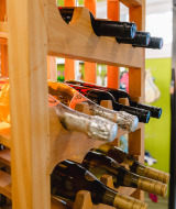 Botellas de vino en un estante de madera junto a una nevera en Camping La Colline parque de vacaciones Belgica Luxemburgo.