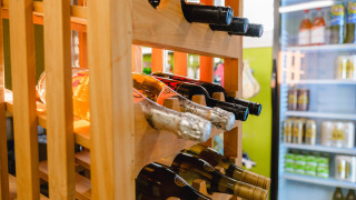 Botellas de vino en un estante de madera junto a una nevera en Camping La Colline parque de vacaciones Belgica Luxemburgo.