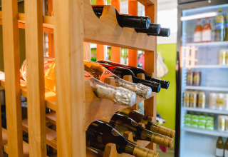 Wine bottles stored in a wooden rack next to a fridge at Camping La Colline holiday park in Belgium Luxembourg.