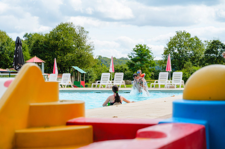 Kinder spielen im Pool mit bunten Bausteinen im Vordergrund im Ferienpark Camping La Colline, Belgien.