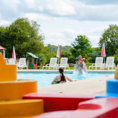 Niños jugando en una piscina con bloques de construcción de colores en primer plano en Camping La Colline, Bélgica.