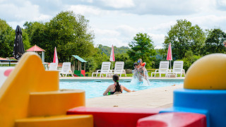 Niños jugando en una piscina con bloques de construcción de colores en primer plano en Camping La Colline, Bélgica.