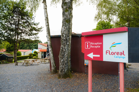 Camping La Colline en Luxemburgo belga, con cartel de recepción Floreal Campings y mesas de picnic afuera.