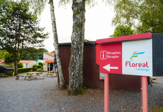 Camping La Colline in Belgisch Luxemburg, met Floreal Campings receptiebord en picknicktafels buiten.