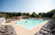 Udendørs swimmingpool med solsenge og gæster, omgivet af grønne bakker på Camping La Garenne i Frankrig.
