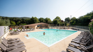 Outdoor swimming pool with sun loungers and guests at Camping La Garenne holiday park, Auvergne-Rhône-Alpes, France.