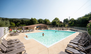 Piscina al aire libre con tumbonas y huéspedes en Camping La Garenne, parque vacacional en Auvernia-Ródano-Alpes, Francia.