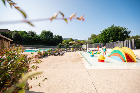 Zona de piscina infantil con juegos de colores y tumbonas en Camping La Garenne, Auvernia-Ródano-Alpes.