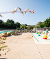 Zona de piscina infantil con juegos de colores y tumbonas en Camping La Garenne, Auvernia-Ródano-Alpes.