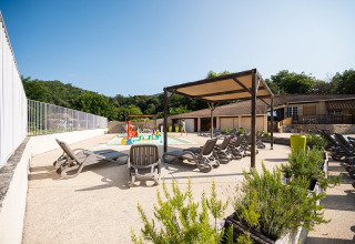 Außenpoolbereich mit Liegestühlen, Sonnenschutz und Spielplatz im Camping La Garenne, Frankreich.