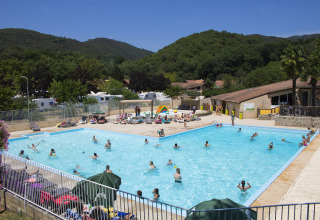 Swimmingpool med gæster på Camping La Garenne feriepark i Auvergne-Rhône-Alpes, omgivet af grønne bakker.