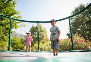 Zwei Kinder spielen auf einem Trampolin bei Camping La Garenne, umgeben von grüner Natur in Frankreich.