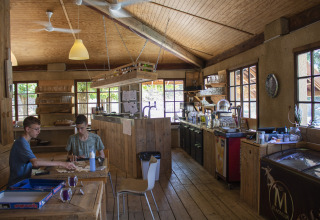 Twee jongens spelen een gezelschapsspel in een houten ruimte bij Camping La Garenne, Auvergne-Rhône-Alpes, Frankrijk.