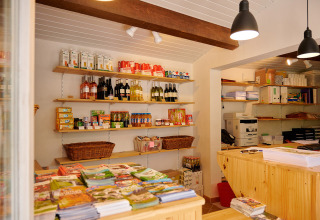 Winkel met schappen vol producten en brochures bij Camping La Garenne vakantiepark in Auvergne-Rhône-Alpes, Frankrijk.