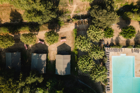 Vista aérea de tiendas y piscina rodeadas de árboles en el Camping La Garenne en Auvergne-Rhône-Alpes, Francia.