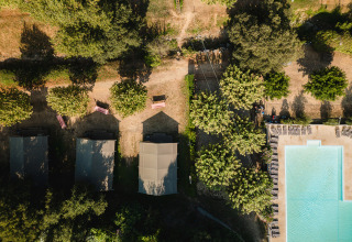 Luftfoto af telte og swimmingpool omgivet af træer på Camping La Garenne feriepark i Auvergne-Rhône-Alpes, Frankrig.
