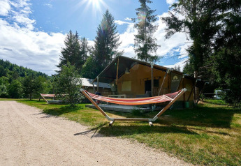 Safaritent Villatent Wood bij Camping de Vaubarlet in Frankrijk met hangmatten en groene omgeving.