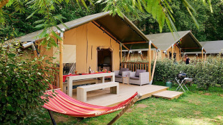 Tienda safari Villatent Wood en Camping Domaine du Logis, Francia, con hamaca y terraza al aire libre.