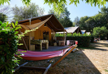 Tienda safari Villatent Nomad en Camping Domaine du Logis, Francia, con porche y hamaca en un entorno natural.