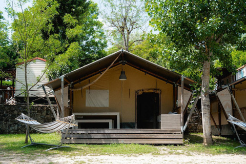 Tienda safari Villatent Wood en Camping Il Poggetto, Italia, con porche y hamaca en el exterior.
