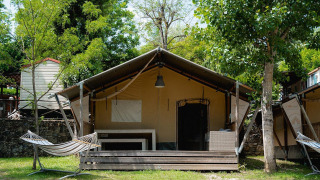 Tienda safari Villatent Wood en Camping Il Poggetto, Italia, con porche y hamaca en el exterior.