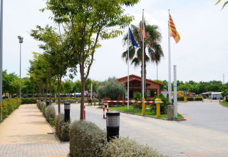 Ingresso del Camping La Masia in Catalogna, Spagna, con bandiere e una casetta di legno alla reception.