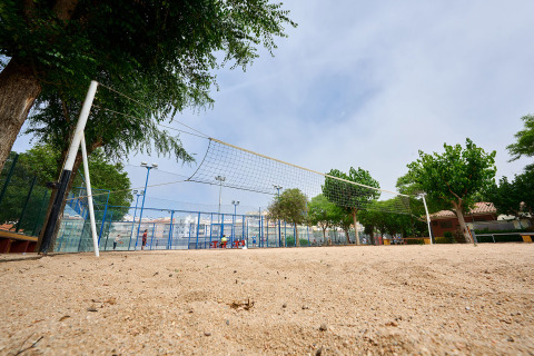 Terrain de volley sur sable avec filet, entouré d'arbres au Camping La Masia, parc de vacances en Catalogne.