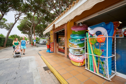 Famiglia passeggia vicino a un negozio di gonfiabili al Camping La Masia, parco vacanze in Catalogna, Spagna.