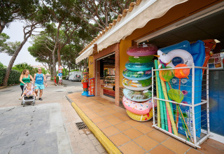 Famiglia passeggia vicino a un negozio di gonfiabili al Camping La Masia, parco vacanze in Catalogna, Spagna.