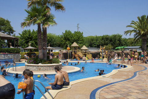 Families and children having fun in the pool area with slides at Camping La Masia in Catalonia, Spain.