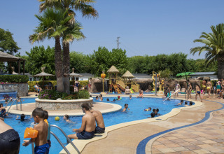 Familias y niños se divierten en la zona de piscinas y toboganes de Camping La Masia en Cataluña, España.