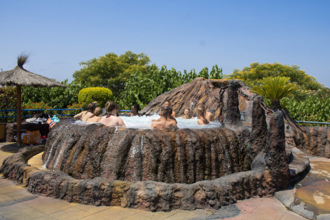 Ospiti rilassati in una vasca idromassaggio a forma di vulcano al Camping La Masia, parco vacanze in Catalogna, Spagna.