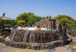 Ospiti rilassati in una vasca idromassaggio a forma di vulcano al Camping La Masia, parco vacanze in Catalogna, Spagna.