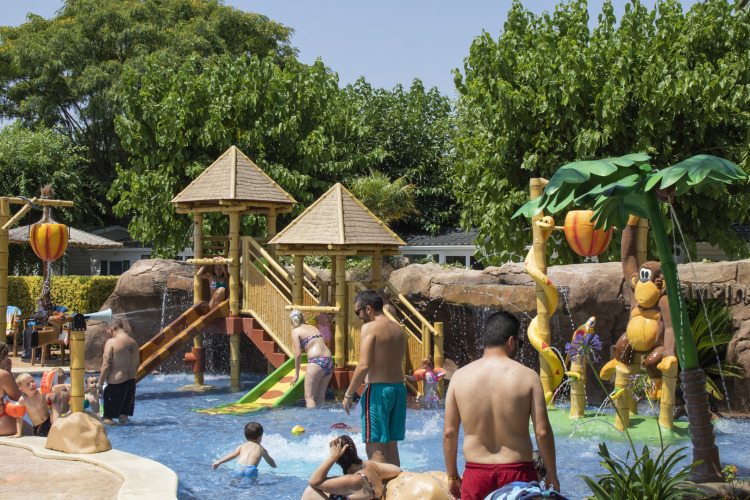 Children and adults enjoy the colorful water playground at Camping La Masia holiday park in Catalonia, Spain.
