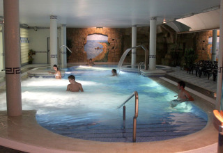 Zona de piscina cubierta en Camping La Masia, Cataluña, España, con huéspedes disfrutando del agua.