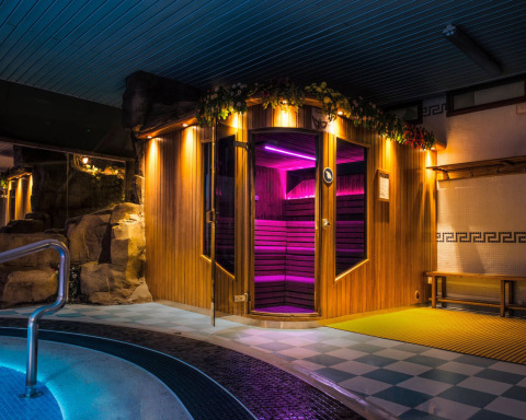 Zona de sauna y piscina interior con luces de colores en Camping La Masia, parque vacacional en Cataluña, España.