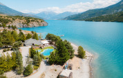 Aerial view of Camping La Presqu’île holiday park by a blue lake and mountains in Provence-Alpes-Côte d’Azur, France.